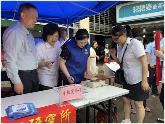 广西桂林市计量测试研究所：计量守护民生  精准赋能生活_计量技术人员为群众进行手机称重标识_5d6086326ac246eb87e40c3a6ce70c7a.png